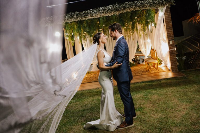 Noivos abraçados diante do altar decorado durante a celebração do casamento