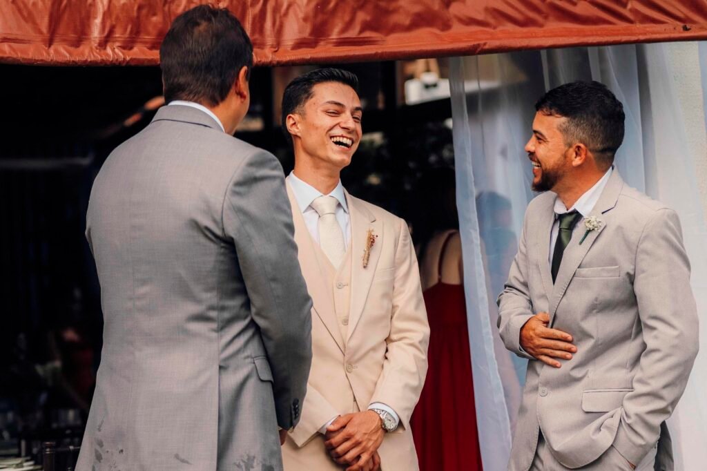 Noivo sorrindo ao lado dos padrinhos durante os preparativos do casamento

